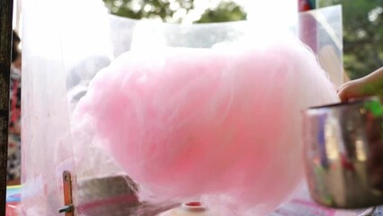 Girl making a big pink sugar cloud at a fair stall