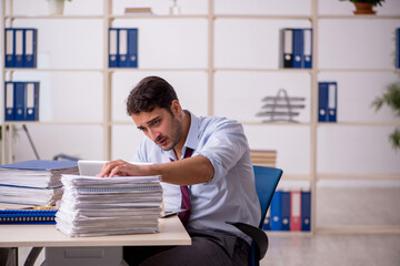 Obraz premium Young male employee and too much work in the office