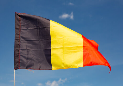 Big flag of Belgium fastened on stick against background of blue sky under daylight