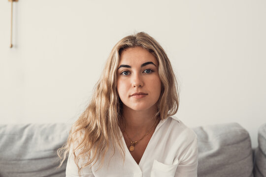 Positive serious millennial model girl home female head shot portrait. Beautiful young adult Caucasian woman looking at camera, posing in apartment. Front profile picture.