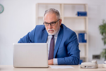 Old male employee working in the office