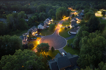 American dream homes at night on rural cul-de-sac street in US suburbs. View from above of brightly...