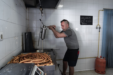 Cocinero echando masa con una herramienta de cocina para freír la masa y hacer los churros, esto es uno de los trabajos mas duros del oficio de churrero.