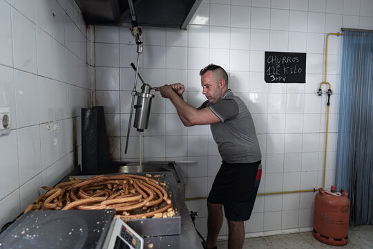 Cocinero echando masa con una herramienta de cocina para fre&iacute;r la masa y hacer los churros, esto es uno de los trabajos mas duros del oficio de churrero.