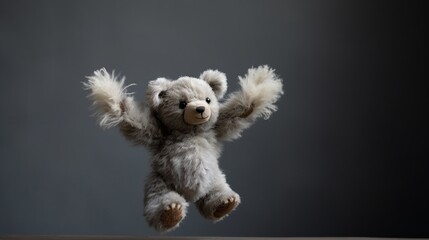 A pocket-sized teddy bear with light grey fur, its arms outstretched in a welcoming gesture