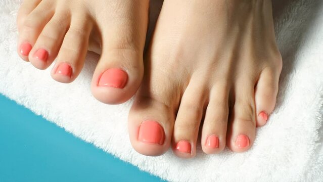 Female feet with pink pedicure on a towel and blue background close up top view.