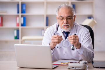 Old male doctor holding goniometer in the clinic
