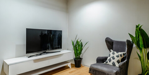 cabinet for tv on the white wall in living room with armchair minimal design 