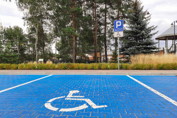 Disabled Parking Road markings and sign. Vacant parking spot near shopping mall. White symbol of wheelchair on blue tiles. City accessibility for people with disabilities. Accessible parking concept. 