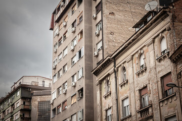 Selective blur on old residential buildings with decaying walls in downtown Belgrade, Serbia, needing heavy renovation with damaged peeling plaster.
