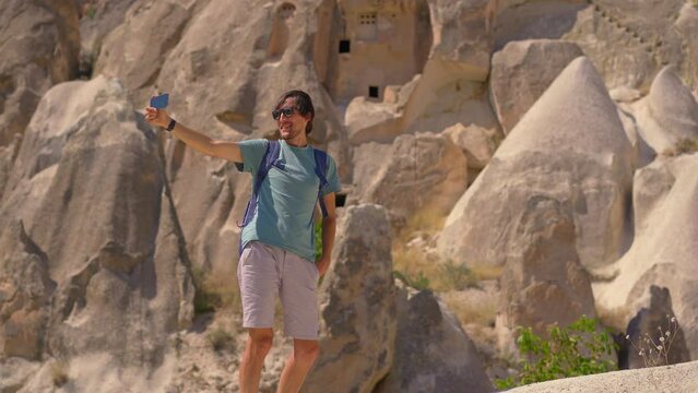 Young man tourist explores the extraordinary rock formations that tell the ancient tales of Cappadocia, Turkey. These surreal rocks, once homes carved by ancient inhabitants, stand as a testament to