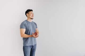 Happy asian man in blue t-shirt and jeans clapping hands stand isolated on white