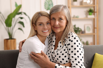 Happy mature mother and her daughter hugging at home