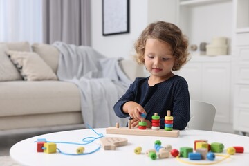 Motor skills development. Little girl playing with stacking and counting game at table indoors