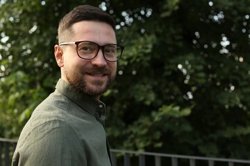Naklejka na ściany i meble Portrait of handsome bearded man in glasses outdoors, space for text