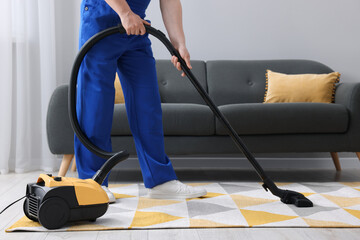 Dry cleaner's employee hoovering carpet with vacuum cleaner in room, closeup - obrazy, fototapety, plakaty