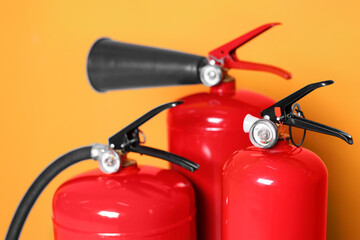 Obraz premium Three red fire extinguishers on orange background, closeup
