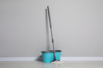 Mop and plastic bucket indoors. Cleaning floor - obrazy, fototapety, plakaty
