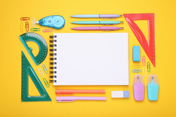 Flat lay composition with notebook and other school stationery on yellow background, space for...