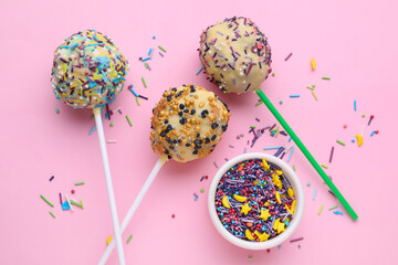 Delicious confectionery. Sweet cake pops and sprinkles on pale pink background, flat lay