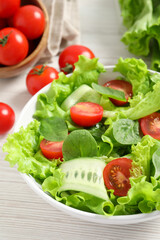 Delicious vegetable salad on white wooden table, closeup