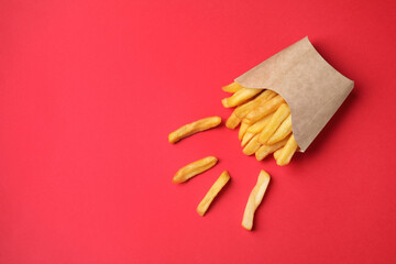 Paper cup with French fries on red table, flat lay. Space for text