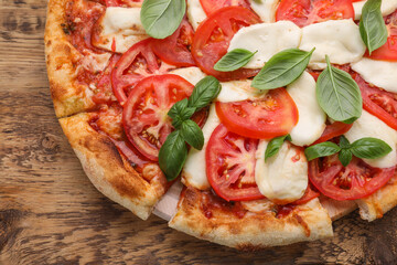 Delicious Caprese pizza with tomatoes, mozzarella and basil on wooden table, top view