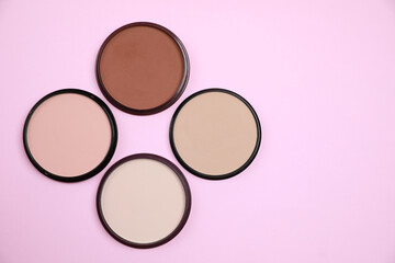 Different face powders on pink background, flat lay. Space for text