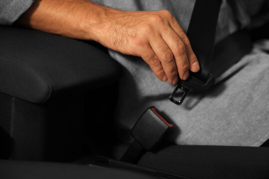 Man fastening safety seat belt in car, closeup