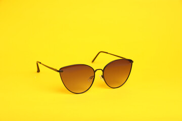 Stylish pair of sunglasses on yellow background