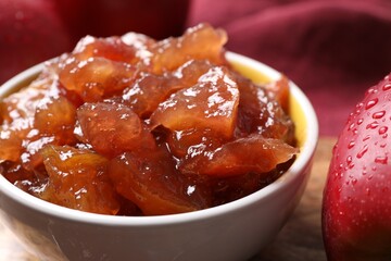 Bowl of delicious apple jam and fresh fruits on wooden table, closeup