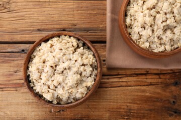 Tasty boiled oatmeal on wooden table, flat lay