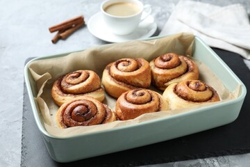 Baking dish with tasty cinnamon rolls on grey textured table, closeup
