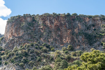 Crag honeycombed with rock-cut tombs towering over Pinara ancient site in Mugla province of Turkey. Pinara was a large city of ancient Lycia.