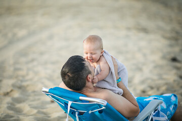 Fototapeta na wymiar Happy Fathers day. Father and baby play on the beach. Dad and him Child together enjoying sunset. Loving single father hugs cute little son.