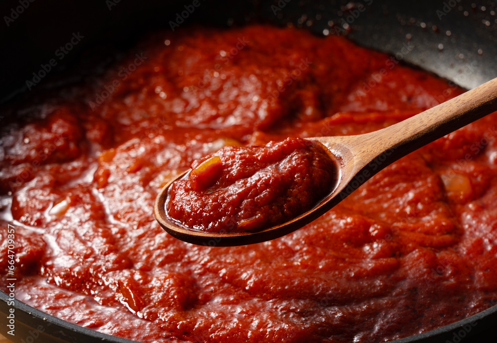 Wall mural scoop up the tomato sauce in the pan with a spoon.