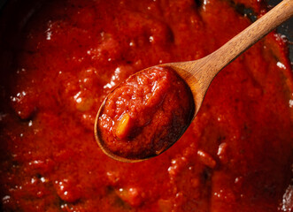 Scoop up the tomato sauce in the pan with a spoon. - obrazy, fototapety, plakaty