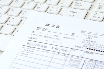 キーボードの上に置かれた請求書—電子帳簿保存法イメージ