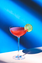 Siesta cocktail drink with tequila, grapefruit and lime juice, syrup and red bitter, liqueur. Blue background, hard light and shadows