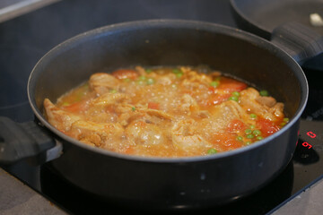 cooking chicken curry in a cooking pan 