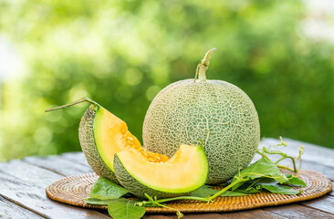 Cantaloupe melon with leaves in blur background. Sweet Orange Melon with leaf on green bokeh background. - obrazy, fototapety, plakaty