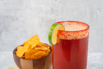 Michelada, Mexican beer drink with chamoy and clamato, with french fries on a white background without people