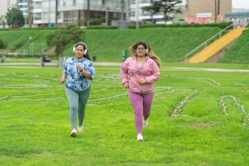 Fototapeta premium Fat women running together while listening to music with headphones