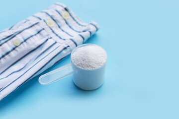 Fototapeta na wymiar Detergent powder in measuring spoon with shirt before washing. Laundry concept.
