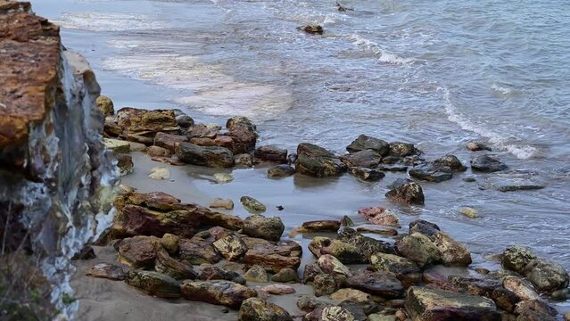 Waves Rolling Into Multicolored Rock Cliff