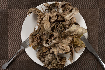 moldy vegetable on a dish with fork and knife lack of food concept