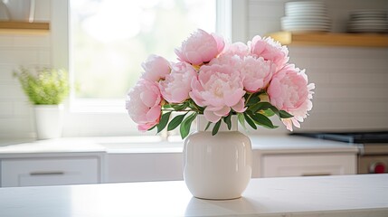 A white vase full of pink flowers is sitting on counter.