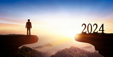 New Year 2024 and businessman on on the mountain at sunset background	