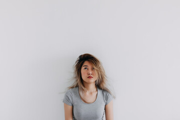 Asian Thai woman wear grey bored face, messy hair, thinking something while looking above at empty...