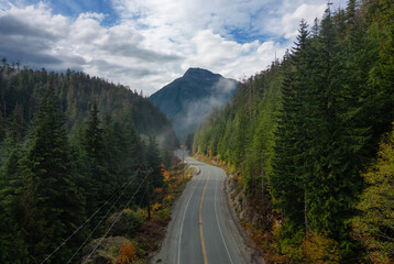 Scenic Highway by Trees with Mountains in Background. Colorful Cloudy Sky.